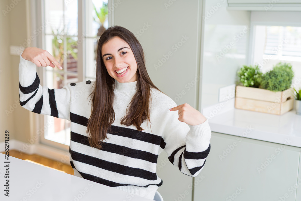 Beautiful young woman wearing stripes sweater looking confident with smile on face, pointing oneself with fingers proud and happy. Beautiful young woman wearing stripes sweater looking confident with smile on face, pointing oneself with fingers proud and happy.