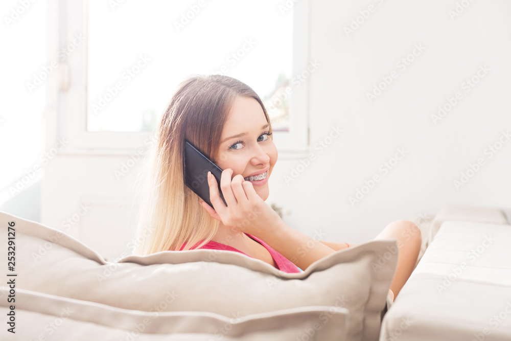 Young woman talking on smartphone on sofa Young woman talking on smartphone on sofa