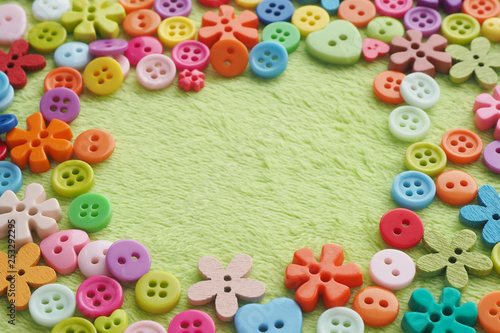 Fotografía many buttons of different shapes, colors and sizes on plush fabric of light green color