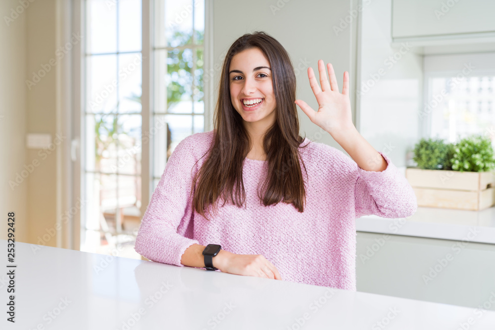 Beautiful young woman wearing pink sweater showing and pointing up with fingers number five while smiling confident and happy. Beautiful young woman wearing pink sweater showing and pointing up with fingers number five while smiling confident and happy.