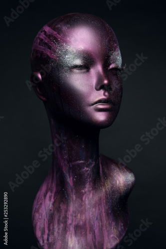 Closeup studio shot of violet woman mannequin with stylish makeup, dark background