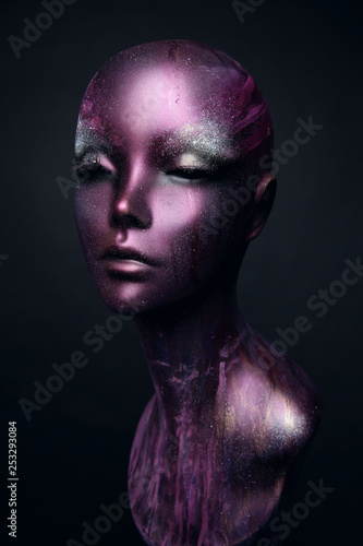 Closeup studio shot of violet woman mannequin with stylish makeup, dark background