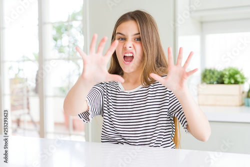 Beautiful young girl kid wearing stripes t-shirt afraid and terrified with fear expression stop gesture with hands, shouting in shock. Panic concept.