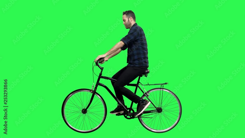 Cute man riding a bicycle over green screen, looking around and upwards, waving hello. No motion blur for optimal keying. Cute man riding a bicycle over green screen, looking around and upwards, waving hello. No motion blur for optimal keying.