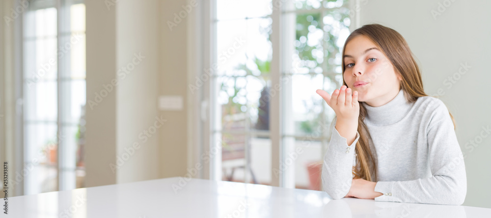 Wide angle picture of beautiful young girl kid wearing casual sweater looking at the camera blowing a kiss with hand on air being lovely and sexy. Love expression. Wide angle picture of beautiful young girl kid wearing casual sweater looking at the camera blowing a kiss with hand on air being lovely and sexy. Love expression.