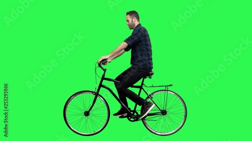 Cute man riding a bicycle over green screen, looking around and upwards, waving hello. No motion blur for optimal keying.