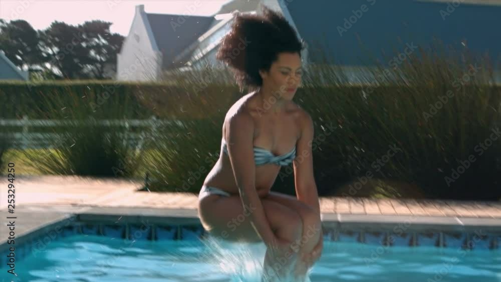 Beautiful woman jumping in swimming pool on a sunny day 4k