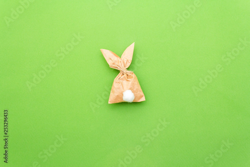 Easter bunny paper gift egg wrapping DIY idea on colorful background. Minimal easter concept, flat lay, copy space.