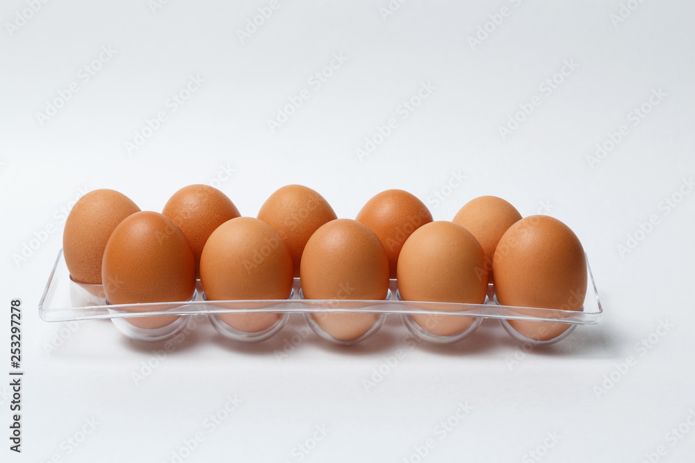 ten brown eggs in a plastic tray on a white background ten brown eggs in a plastic tray on a white background