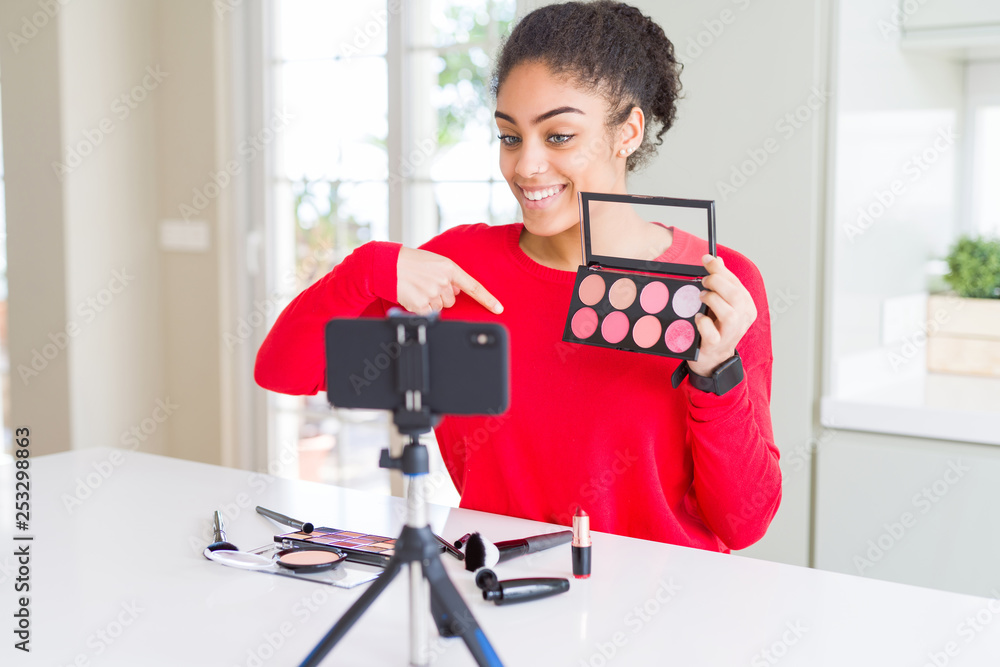 Young african american influencer woman recording make up tutorial with surprise face pointing finger to himself