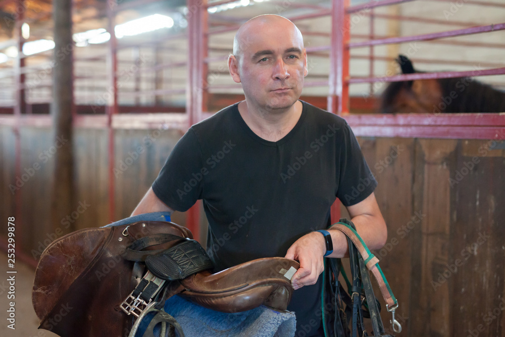 Obraz premium Mature man holding seats and standing at farm with horse
