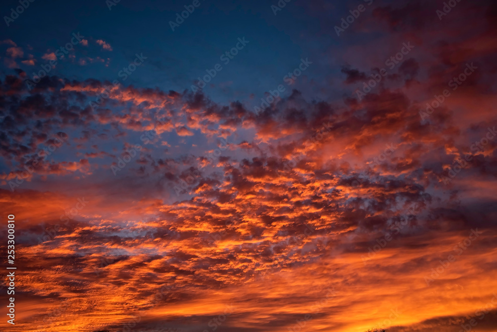 A majestic and awe-inspiration combination of deep blue sky and fiery orange and yellow clouds at sunset.