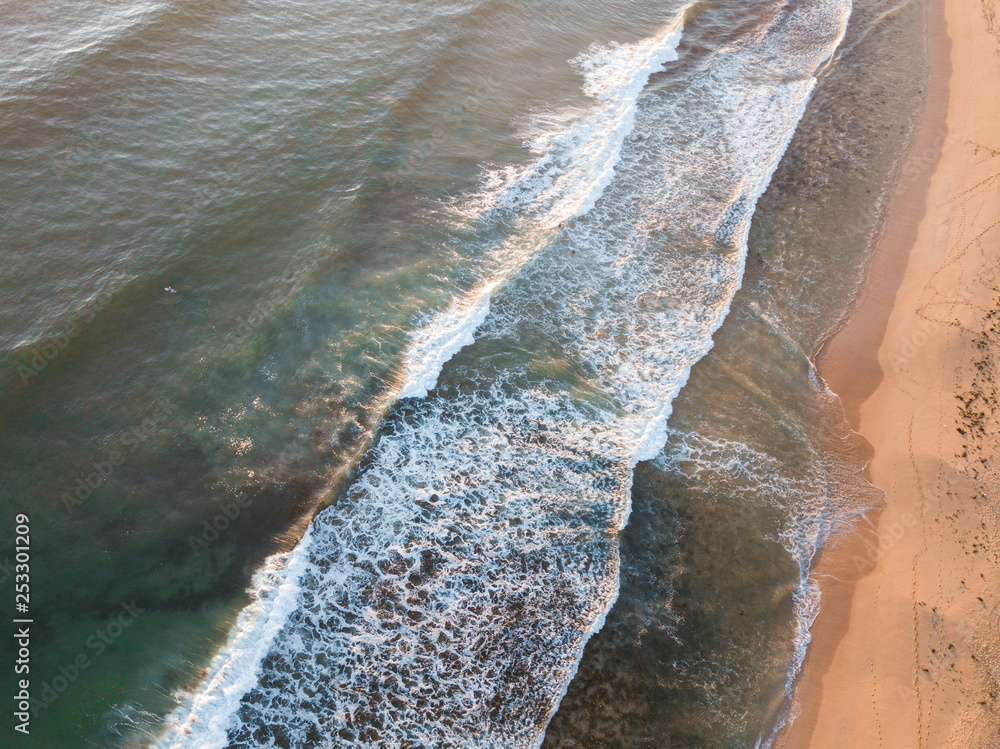 Top down view of wave coming into the sand shore.