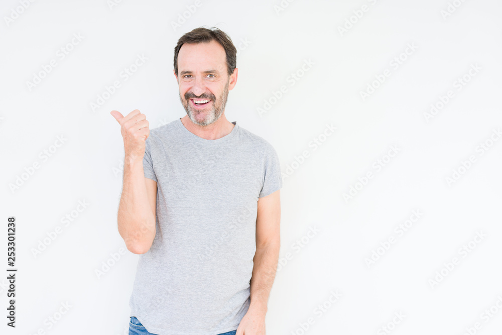 Handsome senior man over isolated background smiling with happy face looking and pointing to the side with thumb up. Handsome senior man over isolated background smiling with happy face looking and pointing to the side with thumb up.