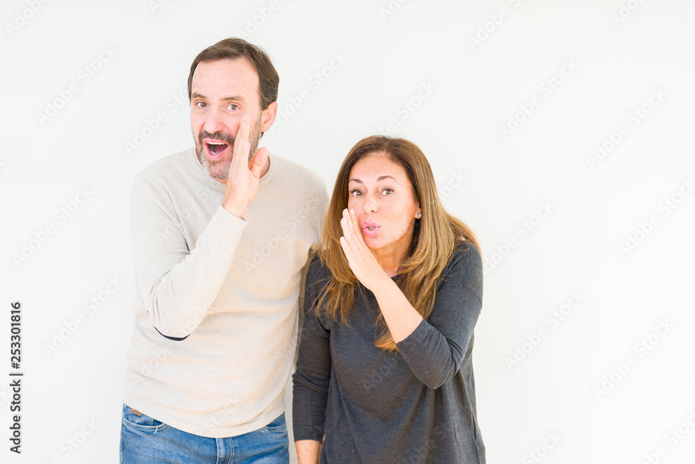 Beautiful middle age couple in love over isolated background hand on mouth telling secret rumor, whispering malicious talk conversation Beautiful middle age couple in love over isolated background hand on mouth telling secret rumor, whispering malicious talk conversation