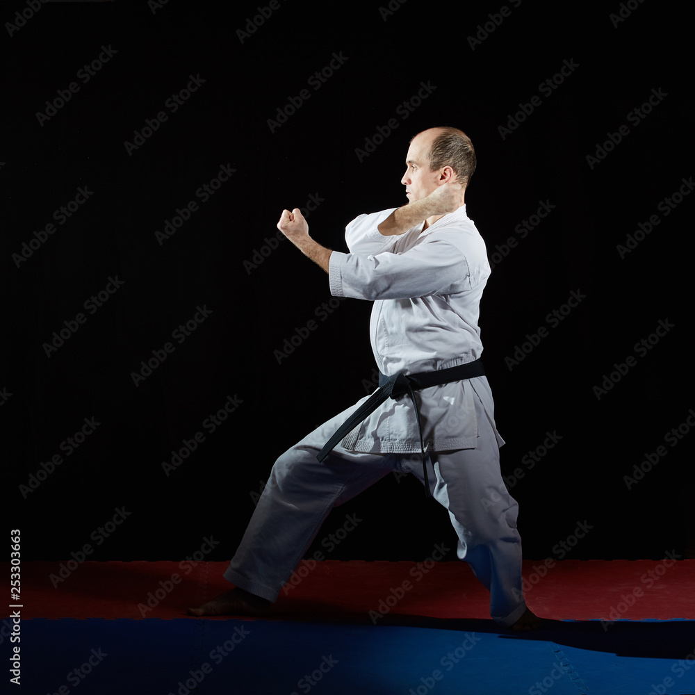 On red and blue tatami active athlete trains formal karate exercises