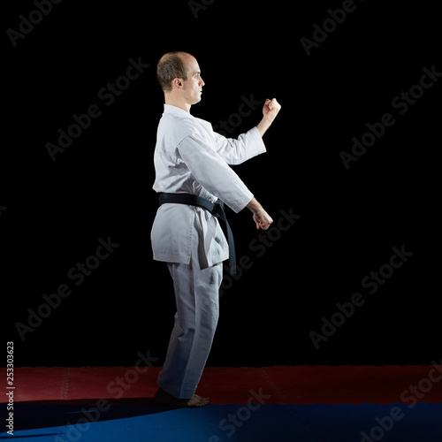 Active athlete does formal karate exercises on red and blue tatami