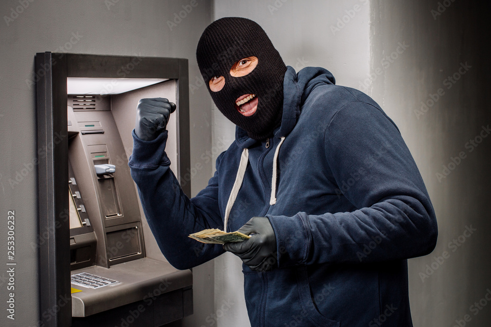 Thief. Hacker stealing money from ATM machine. Phishing, ATM skimming Thief. Hacker stealing money from ATM machine. Phishing, ATM skimming