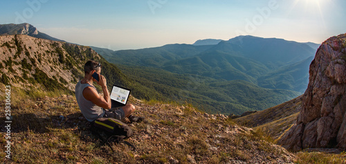 Foto man freelancer with laptop, call by cellphone, on beauty mountains landscape