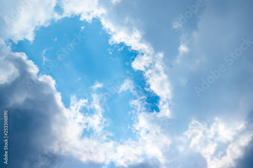 Blue sky and white clouds blue sky on a bright day with white clouds coming in floating come to cover sun causes a white beam causing beauty in the sky.