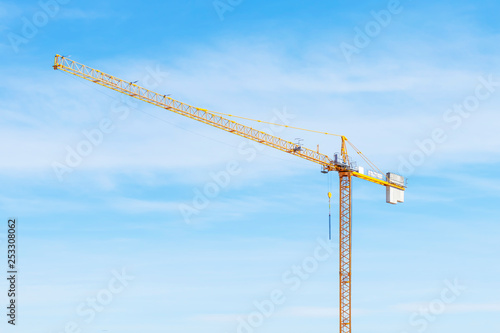 Tower crane with slings against blue sky