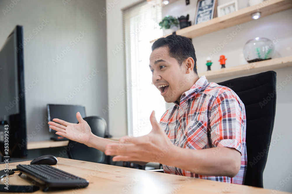 excited asian businessman winning a deal when looking at his pc in the office excited asian businessman winning a deal when looking at his pc in the office