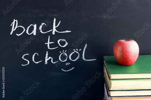 Fototapeta Naklejka Na Ścianę i Meble -  Inscription text Back to school on black chalkboard and red apple on stack books textbooks, Concept education