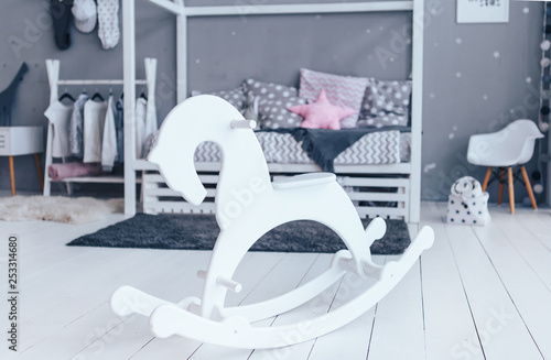 White wooden rocking horse in stylish wooden children room