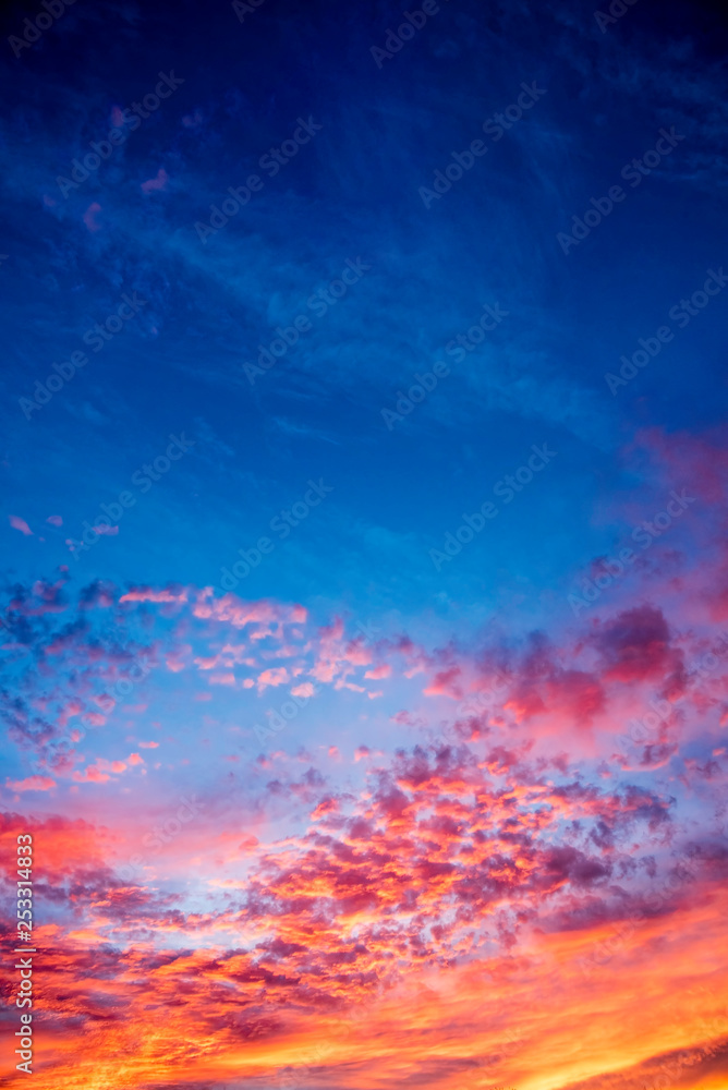 Naklejka premium A majestic and awe-inspiration combination of deep blue sky and fiery orange and yellow clouds at sunset.