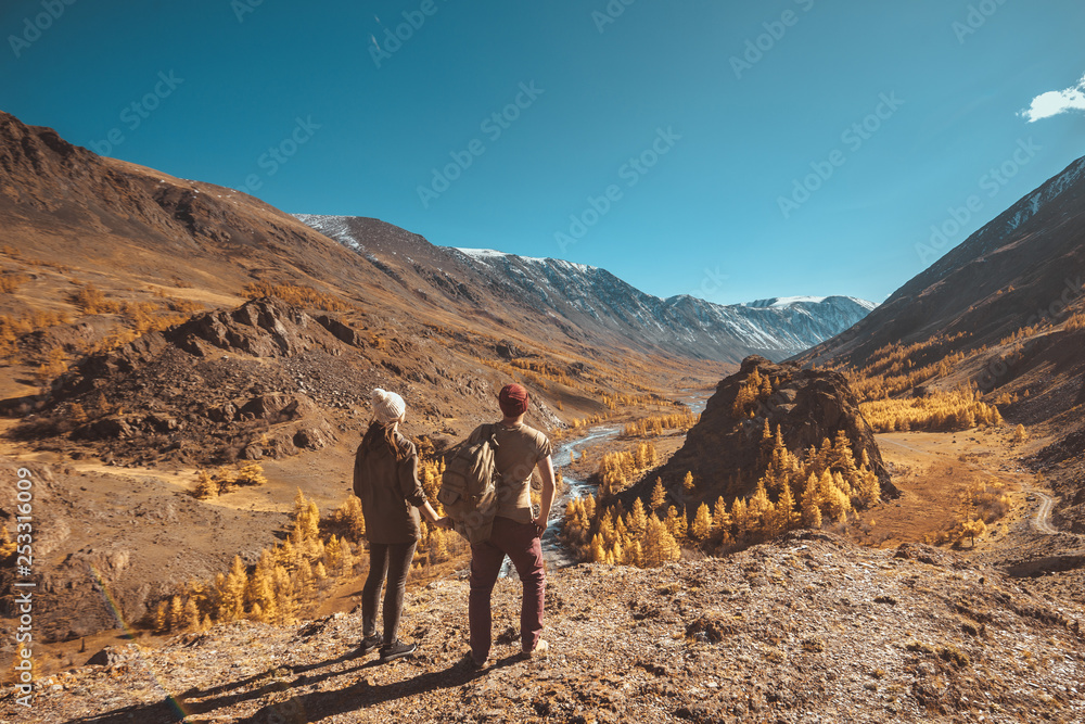 Two travellers looks at mountains and valley