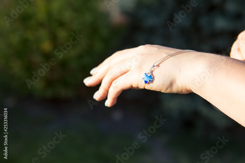 Female hand is holding a blue necklace. Enamel decoration © Svetlana