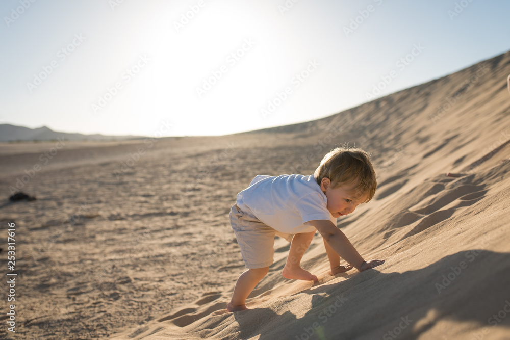 Handsome baby boy climbing on a sand dune. Handsome baby boy climbing on a sand dune.