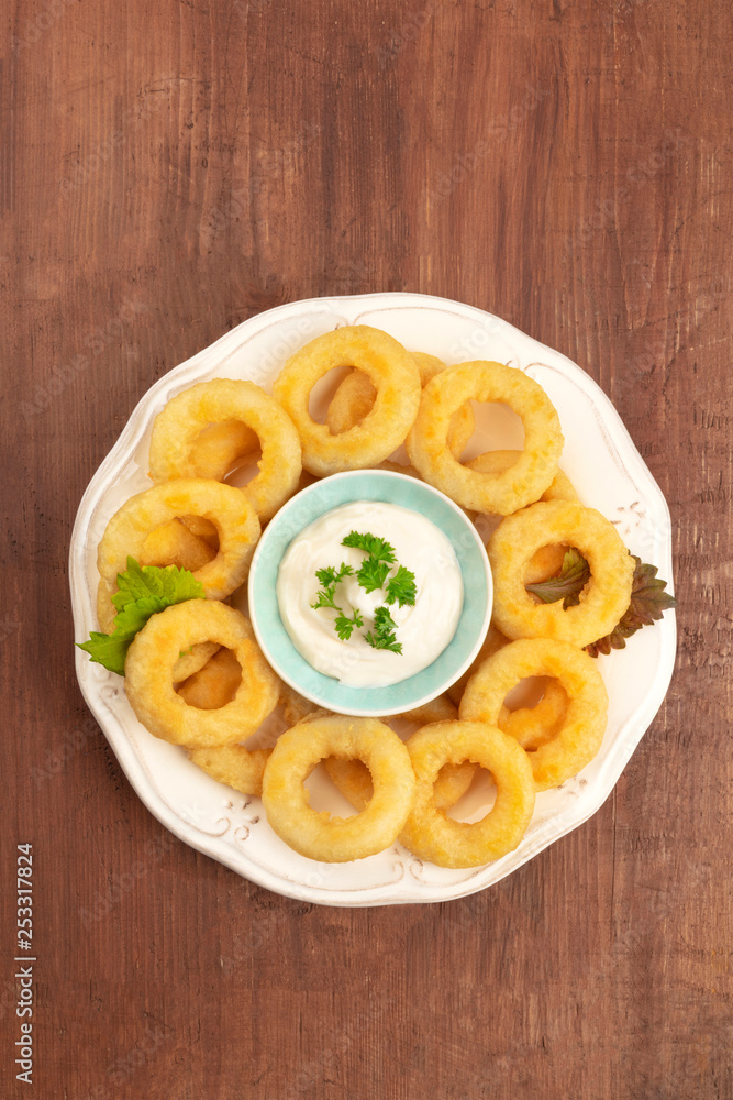 An overhead photo of squid rings with mayonnaise on a dark rustic wooden background with a place for text An overhead photo of squid rings with mayonnaise on a dark rustic wooden background with a place for text