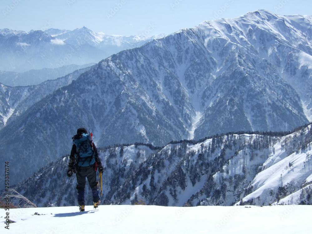A climber walking on a snowy ridge - 雪の尾根を歩く登山者 A climber walking on a snowy ridge - 雪の尾根を歩く登山者