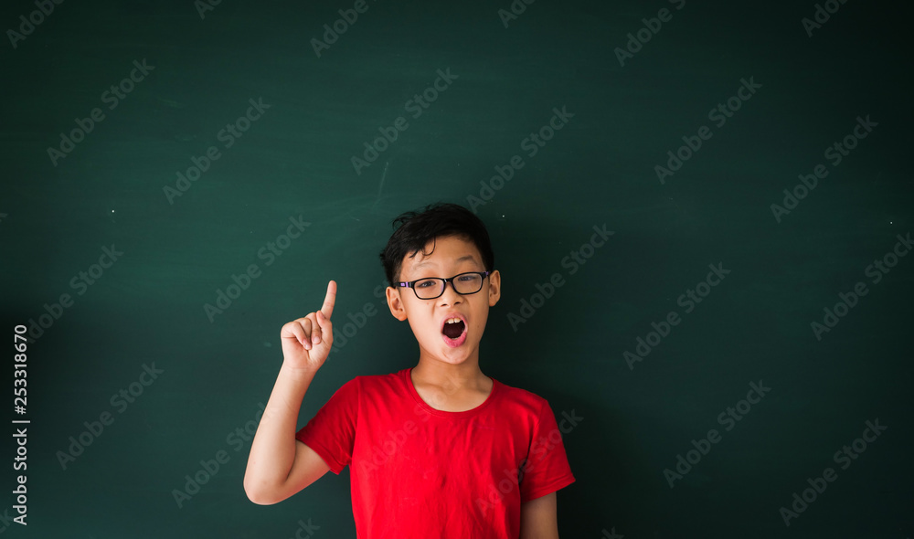 Asian boy with book on blackboard background education school classroom concept
