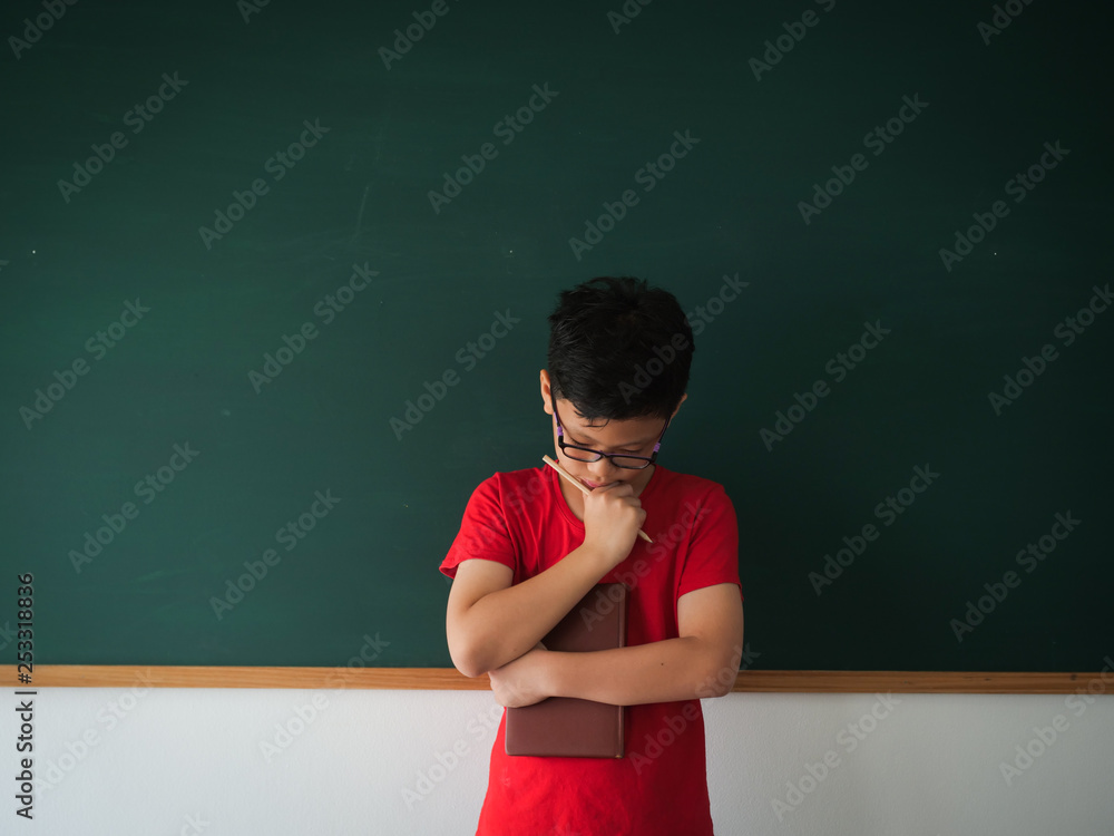 Asian boy with book on blackboard background education school classroom concept