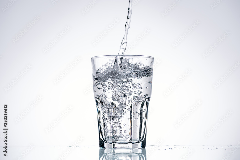 water pouring in drinking glass on white background with backlit and copy space
