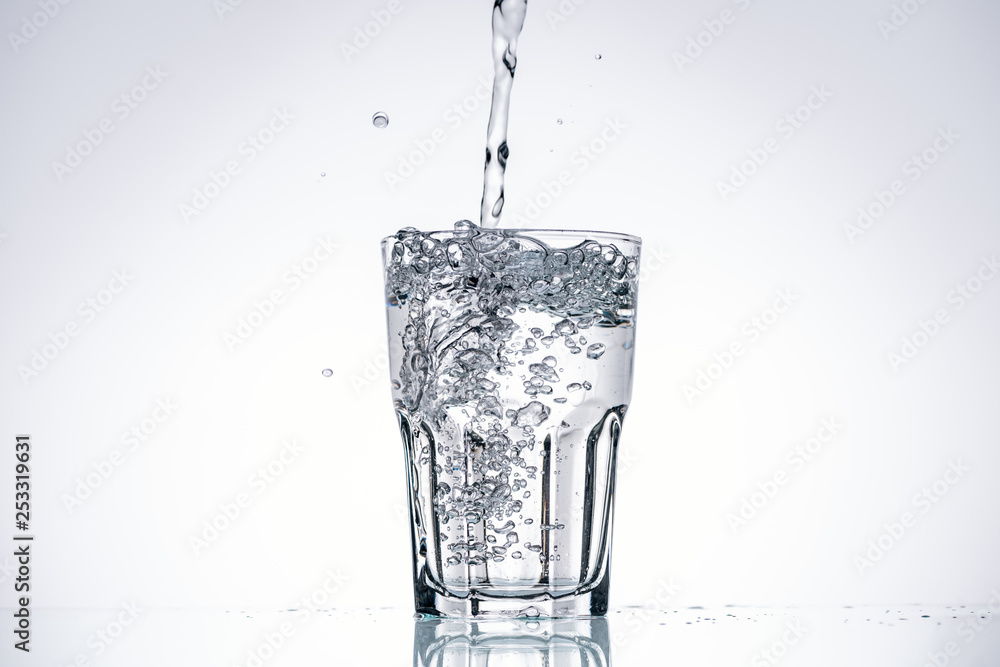 water pouring in drinking glass on white background with backlit and copy space water pouring in drinking glass on white background with backlit and copy space
