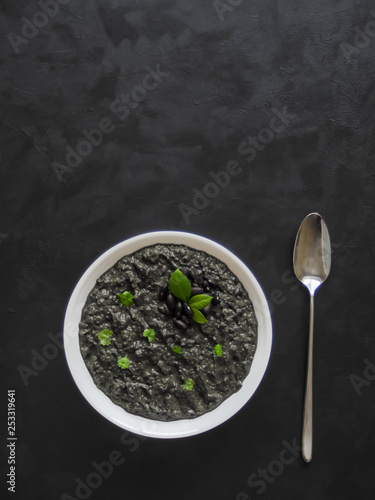 Soup puree of black beans on black background. 