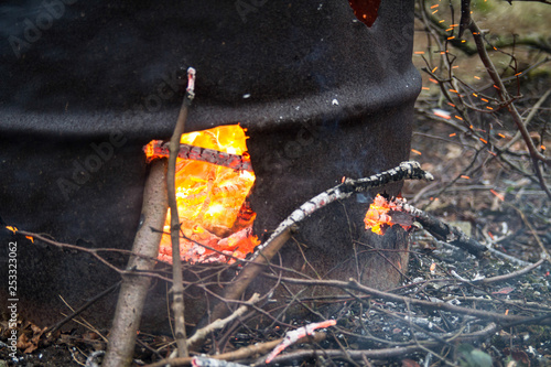 Branches and twigs being burnt in a garden incinerator. Sparks, flames and ash are visible.