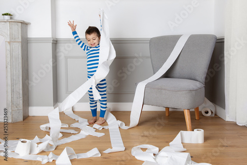 Young boy making mess with toilet paper roll