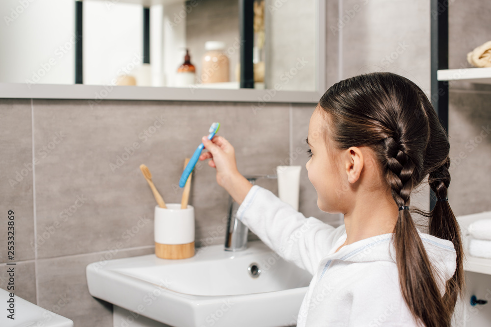 cute child in white bathrobe taking toothpaste in bathroom cute child in white bathrobe taking toothpaste in bathroom