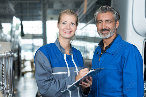 portrait of a female and male mechanic in bus depot