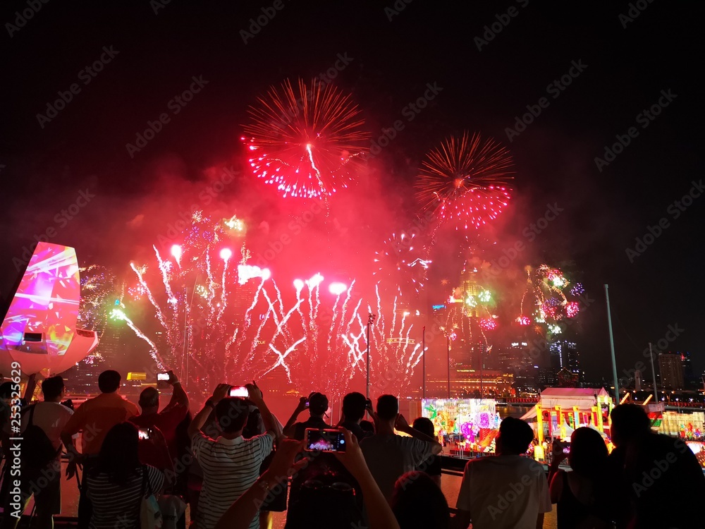 The crowd celebrates the Chinese New Year in Singapore. Silhouettes of people watching a fireworks display. Stock photo.