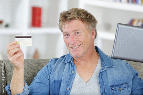 mature man using his laptop and holding his credit card