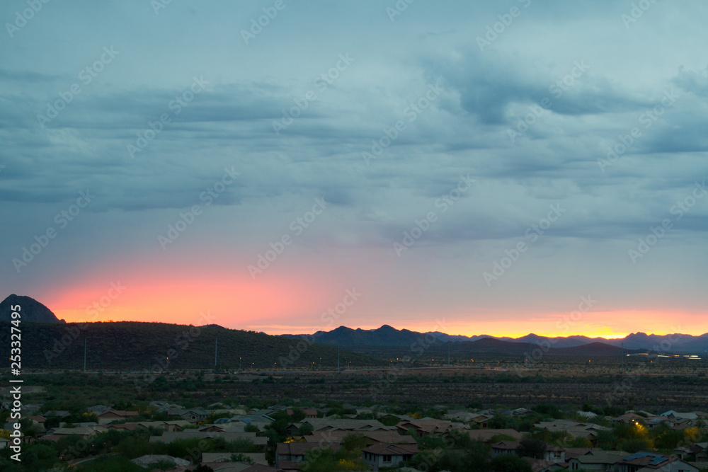 Desert Sunset with Mountains and Clouds and sunlight reflecting off the bottom of the clouds.