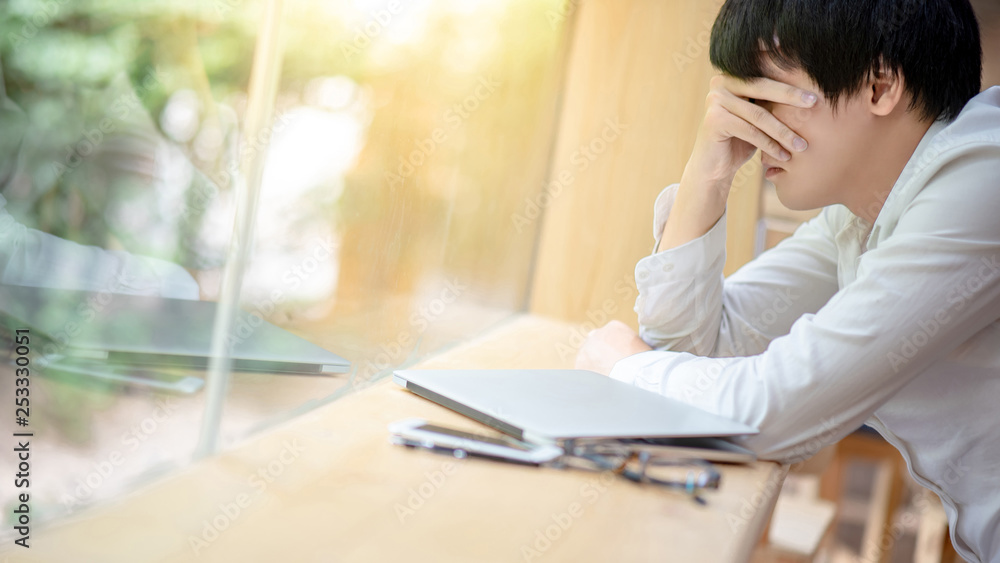 Overworked Asian businessman feeling stressed and tired from business problem while working with laptop computer in cafe. Migraine symptoms or headache from work failure. Overworked Asian businessman feeling stressed and tired from business problem while working with laptop computer in cafe. Migraine symptoms or headache from work failure.