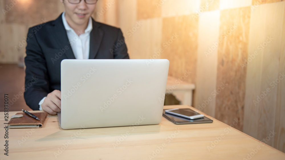 Asian businessman wearing black suit working with modern laptop computer on wooden table in the cafe. Work smart in digital age. Internet of things (IOT) concept Asian businessman wearing black suit working with modern laptop computer on wooden table in the cafe. Work smart in digital age. Internet of things (IOT) concept