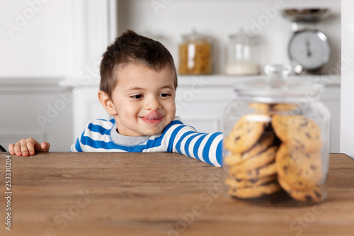 Child reaching at cookie jar with sticking tongue