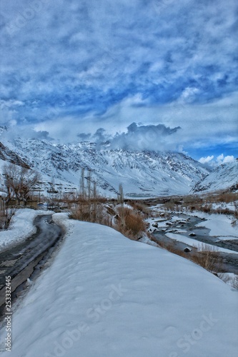 A beautiful view of a valley wit road on left and river on right in ladakh india covered with snow. 